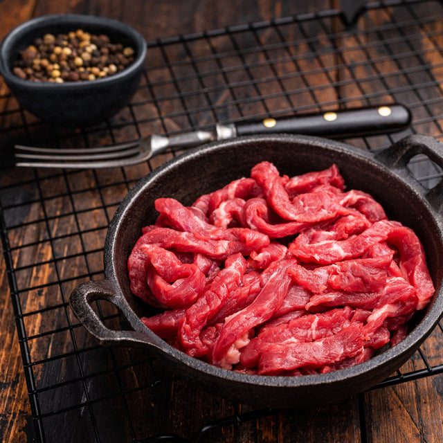Thin-sliced raw carne asada beef in a cast iron pan — Stittsworth Meats, Bemidji MN