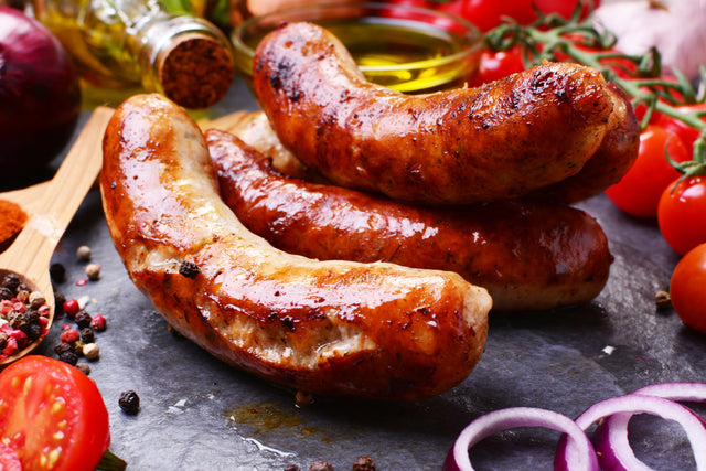 Stittsworth breakfast sausage links, golden-cooked, on a rustic board with herbs and peppercorns