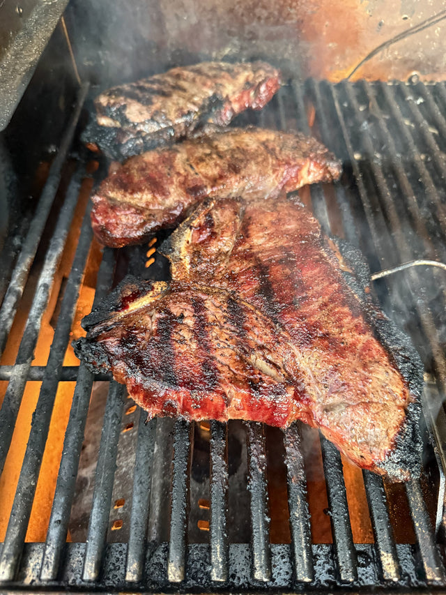 Stittsworth T-bone steaks grilling over open flame — Bemidji, MN