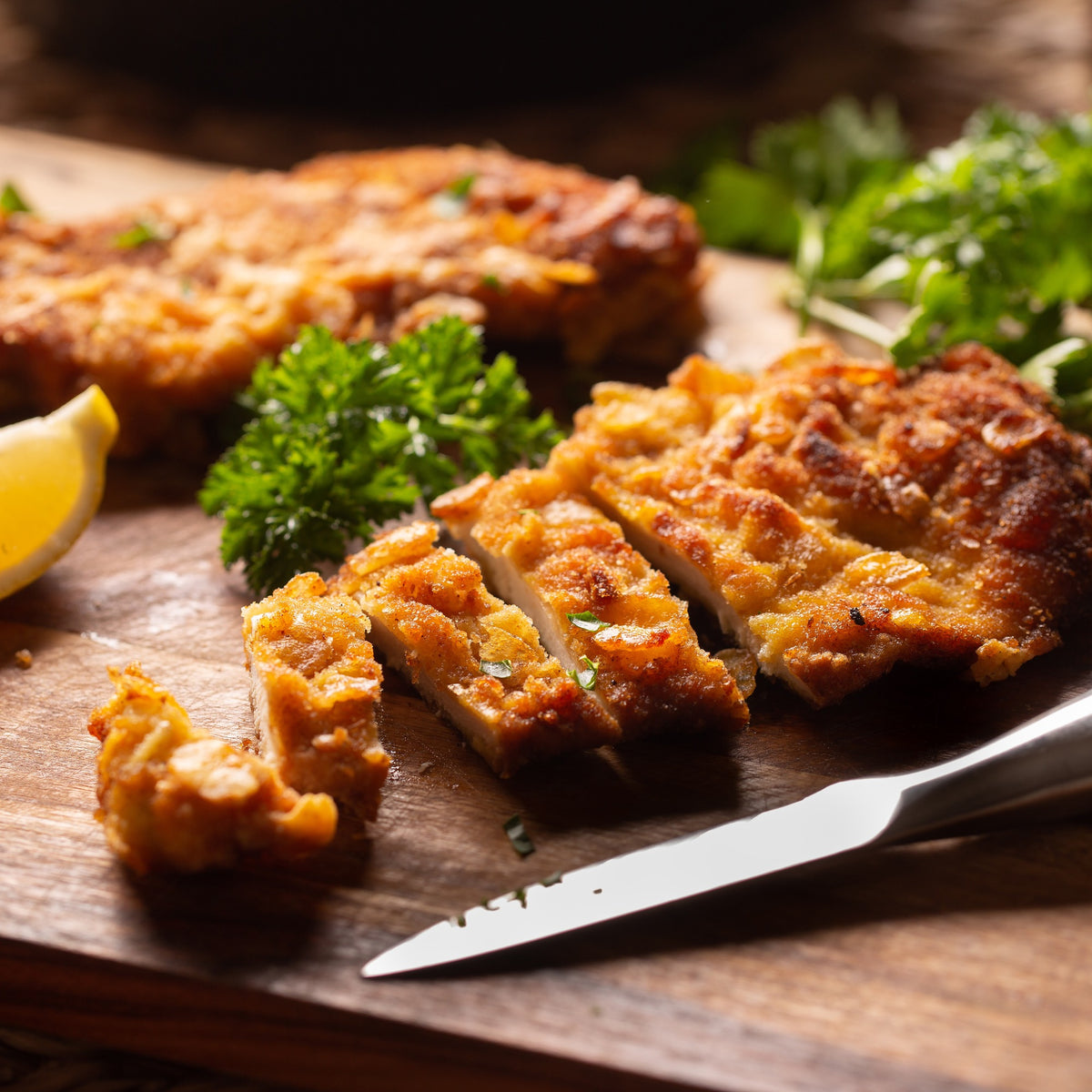 Crumb-crusted chicken breast sliced on a wooden board — Stittsworth Meats, Bemidji MN